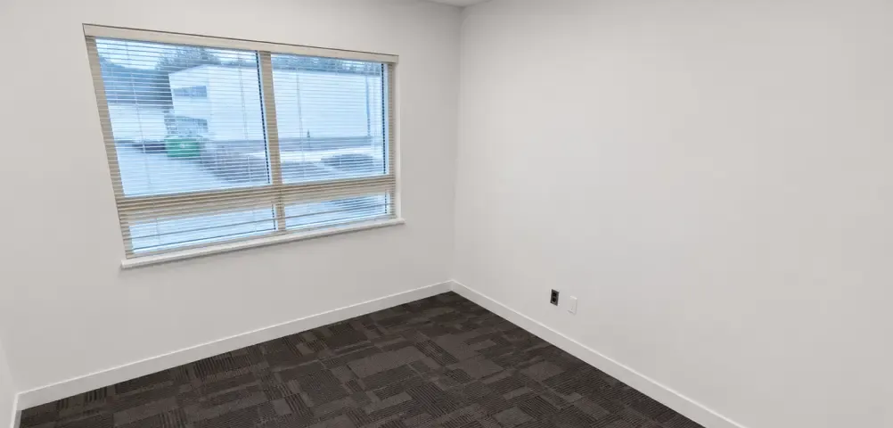 Newly renovated commercial private office space with modern dark carpet and freshly painted walls, a commercial interior project by Pacific Coast Contracting.